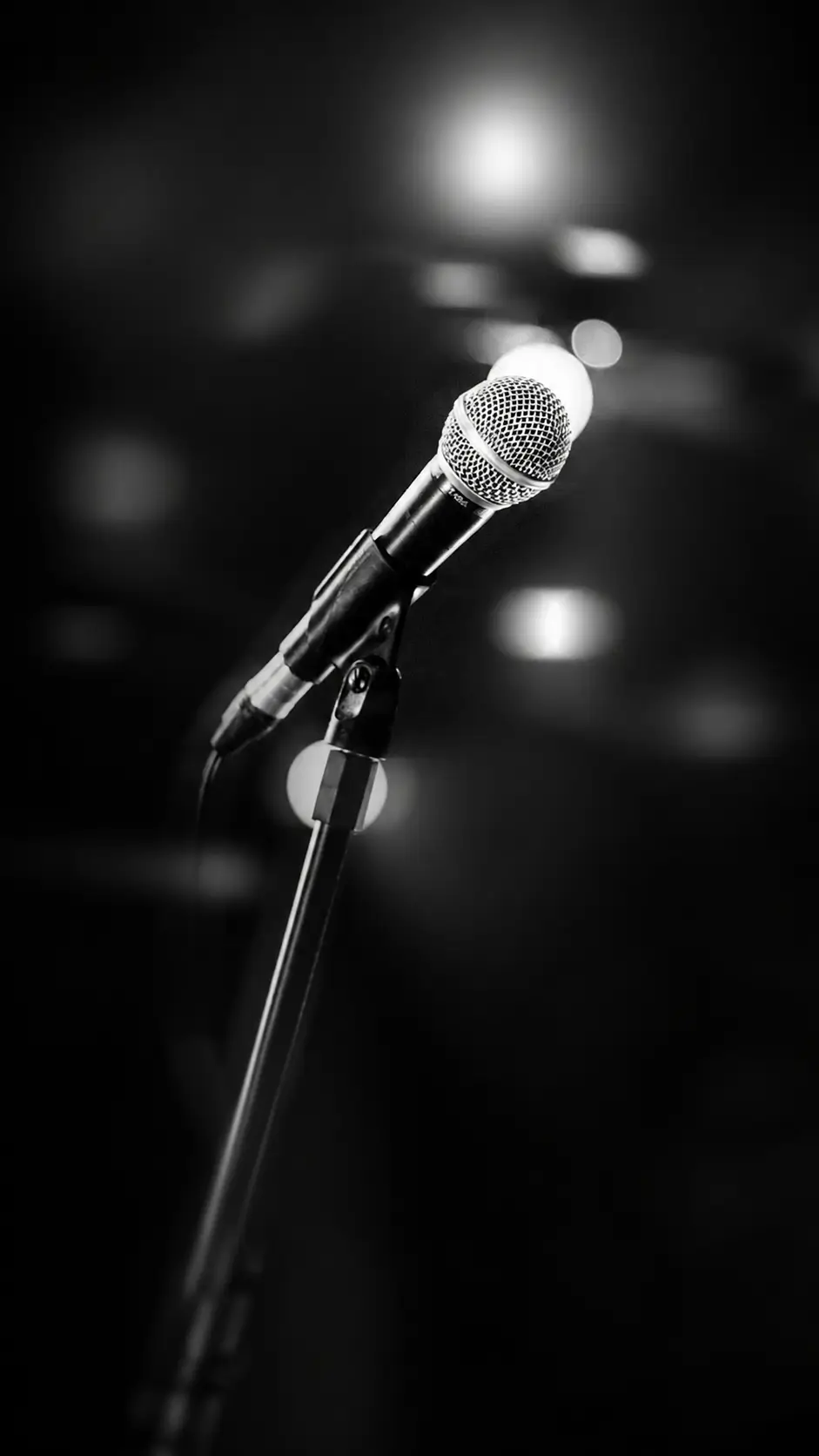 Micrófono en un escenario con luces de fondo, esperando una voz nueva